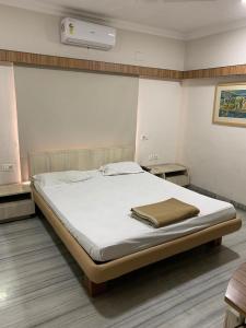 een slaapkamer met een groot bed met witte lakens bij Ballygunge Guest House in Calcutta