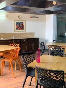 een restaurant met tafels en stoelen met een roze fles erop bij Ballygunge Guest House in Calcutta