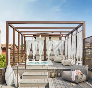 an outdoor patio with a pool and white curtains at Enjoy Garda Hotel in Peschiera del Garda