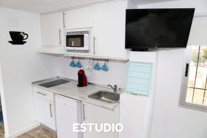 cocina con armarios blancos, fregadero y microondas en Villa Ana Apartments en Benidorm