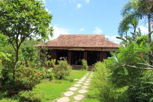 a house in a garden with a path leading to it at Gite Nam Hien Mekong in Cho Lach