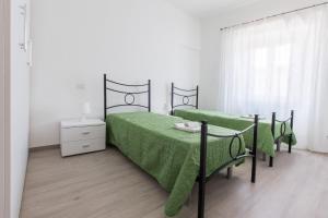 a bedroom with two beds with green sheets and a table at La casa del tenore in Recanati