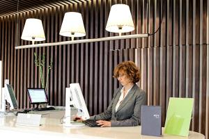 a woman sitting at a desk using a laptop computer at Enjoy Garda Hotel in Peschiera del Garda