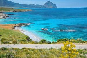 una playa con agua azul y montañas de fondo en Casa Sarina, en San Vito lo Capo