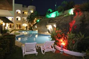 two chairs and a swimming pool at night at Hotel Alikar in Santa Cruz Huatulco