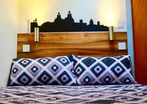 a bed with a wooden headboard and two pillows at The Liverpool Pod Travel Hostel in Liverpool