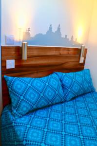 a blue bed with a wooden headboard and a blue pillow at The Liverpool Pod Travel Hostel in Liverpool