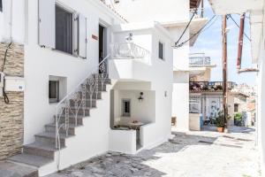 una casa blanca con escaleras en una calle en SKIA-Cosy Living, en Skiathos
