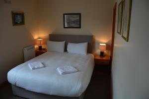 ein Schlafzimmer mit einem weißen Bett mit zwei Handtüchern darauf in der Unterkunft Killarney Country Club in Faha