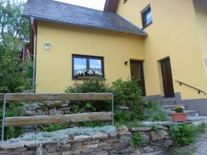 a yellow house with a retaining wall and a fence at Erzgebirgshütte in Pobershau