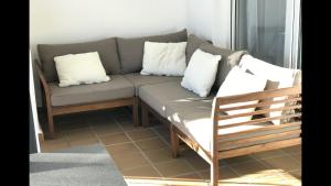 a couch with white pillows and a wooden chair at MI CAPRICHO 3-5 BEACHFRONT- Apartment with sea views in Costa del Sol in Mijas Costa +45 photos