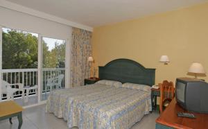 a bedroom with a bed and a tv and a balcony at Es Pi 2 in Playa Migjorn