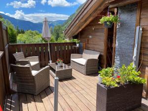 a wooden deck with wicker chairs and an umbrella at Le Cocoon de Sarah in Chamonix-Mont-Blanc