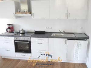 a white kitchen with a stove and a sink at Ihre Ferienwohnung bayrisch mehr... in Gstadt am Chiemsee