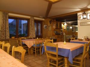 a dining room with tables and chairs and a kitchen at Agriturismo Prati Oitzinger in Valbruna