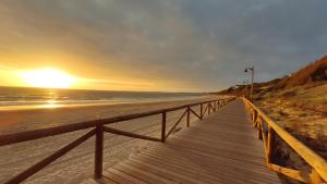 een houten promenade die bij zonsondergang naar het strand leidt bij Apartamentos Bahía Blanca in El Puerto de Santa María