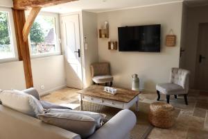 a living room with a couch and a tv at Les maisons de Charlotte (2) in Glanville
