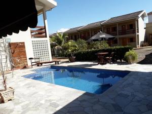 a swimming pool in front of a house with an umbrella at Ville Park Hotel in Ourinhos