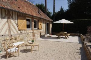 a patio with a table and an umbrella at Les maisons de Charlotte (2) in Glanville