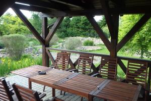 a wooden table and chairs on a patio with a garden at U Aptekarzy in Szymbark