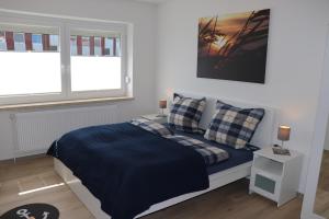 a bedroom with a bed with a blue blanket and two windows at Ferienwohnung Wippsteert - 5 Sterne - mit Balkon und Pkw Stellplatz in Emden