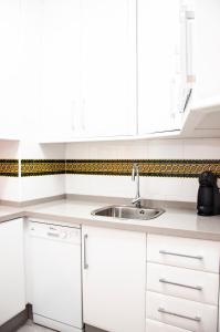 a kitchen with white cabinets and a sink at AlohaMundi Zaragoza III in Seville