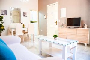 ein Wohnzimmer mit einem Tisch und einem TV in der Unterkunft AlohaMundi Zaragoza III in Sevilla