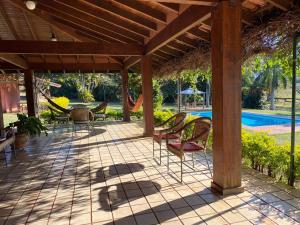 a patio with chairs and a hammock next to a pool at Chácara San Diego - Brotas in Brotas