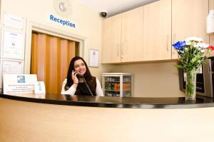 a woman sitting at a counter talking on a cell phone at Comfort Inn Edgware Road W2 in London