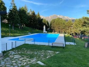 una piscina con un banco en el césped en Chalet Los Ibones - Lodge Formigal, en Formigal