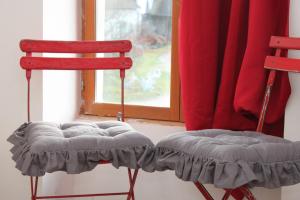 2 chaises rouges assises devant une fenêtre dans l'établissement A la Ferme de la Joie - Chambres d'Hôtes, à Chevannes
