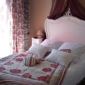 een slaapkamer met een bed met een witte sprei en kussens bij Chambres d'hôtes - Au Domaine des Camélias in Pluméliau