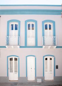 un edificio azul y blanco con puertas y ventanas blancas en B&B LE TRE CHIOCCIOLE, en SantʼAntìoco