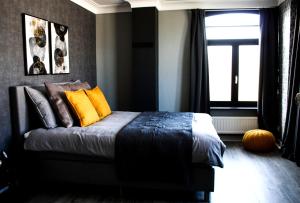 Un dormitorio con una cama con almohadas amarillas y una ventana en A Bascule Bed and Breakfast Maastricht, en Riemst