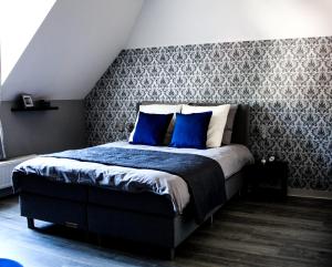 een slaapkamer met een groot bed met blauwe kussens bij A Bascule Bed and Breakfast Maastricht in Riemst
