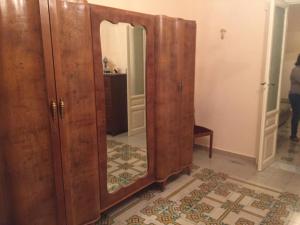 een grote houten kast met een spiegel in een kamer bij casa MARINO in Caltabellotta