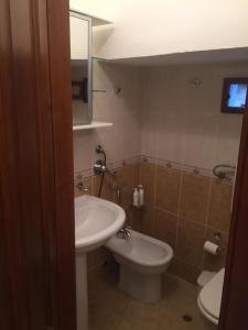 een badkamer met een wastafel, een toilet en een spiegel bij casa MARINO in Caltabellotta