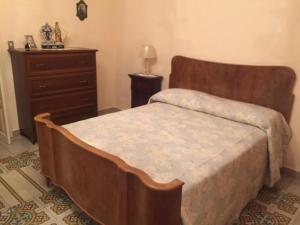een slaapkamer met een houten bed en een dressoir bij casa MARINO in Caltabellotta