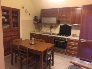 una cocina con armarios de madera y una mesa con sillas. en casa MARINO, en Caltabellotta
