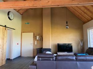 a living room with a couch and a tv at De Kasseihoeve in Kalken