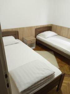 two beds in a room with white sheets at Domaćinstvo Trifunović in Pretrešnja
