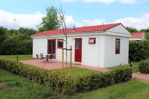 Cabaña blanca pequeña con techo rojo en Hofgalow Chalet op camping "De Stal" en Drijber