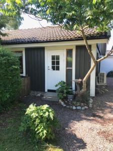 una pequeña casa con una puerta blanca y un árbol en 3:e Sandbank, en Beddinge Strand