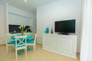- un salon avec une télévision et une table avec des chaises dans l'établissement Holiday House Solemare, à Orikum