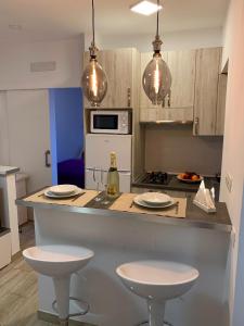 une cuisine avec deux tabourets et un comptoir avec deux verres dans l'établissement Cómodo apartamento en el corazón dé Tenerife, à La Laguna