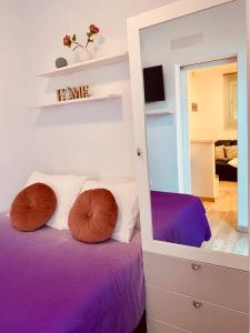 - une chambre dotée d'un lit avec des draps violets et un miroir dans l'établissement Cómodo apartamento en el corazón dé Tenerife, à La Laguna