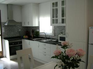 eine Küche mit weißen Schränken und einer Vase aus rosa Rosen in der Unterkunft Casa Fuente Alta in Otívar