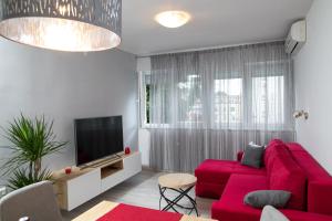 a living room with a red couch and a tv at Dimani in Split