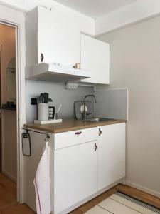 cocina con armarios blancos y encimera en Lägenhet / studio i centrala Båstad, en Båstad
