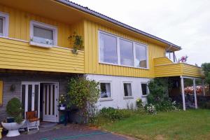 a yellow and white house with a porch at Risør Bed & Breakfast, Randvik Strand in Risør